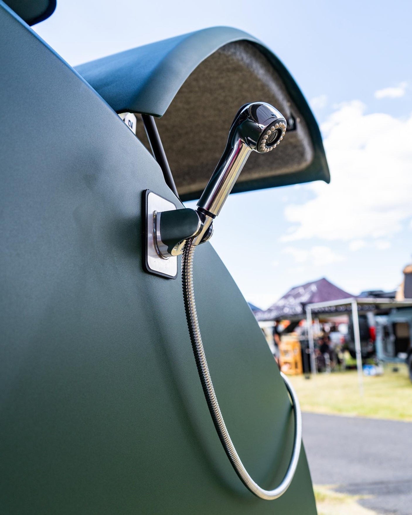 Outdoor shower on an RV rental. Handy chrome fixture on a green camper, ready for adventures & refreshing washes.