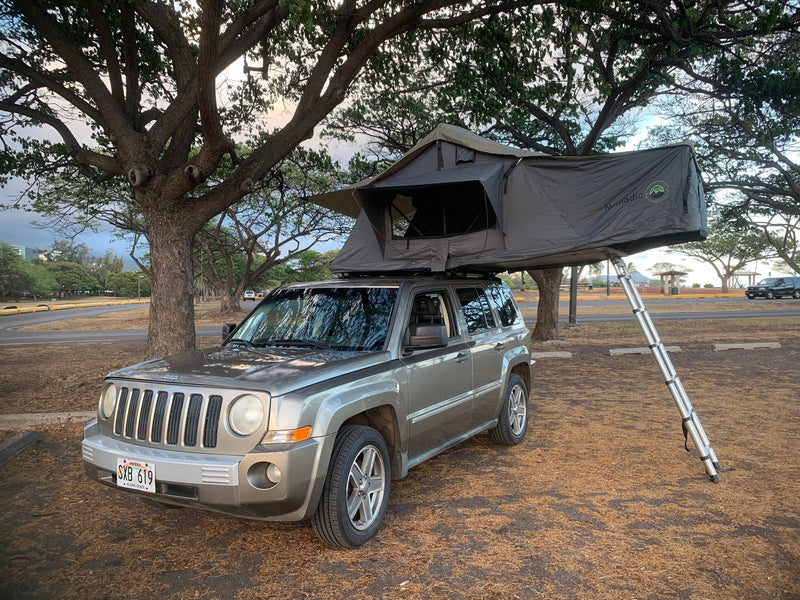 Grey Jeep Patriot with an open Nomadic rooftop tent & ladder. A compact RV rental for adventurous camping. — photo 3