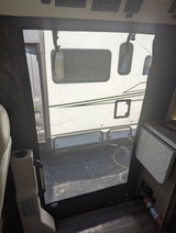 From an RV rental interior, a screen door shows a parked camper outside. Cabin controls are above, fire extinguisher below.
