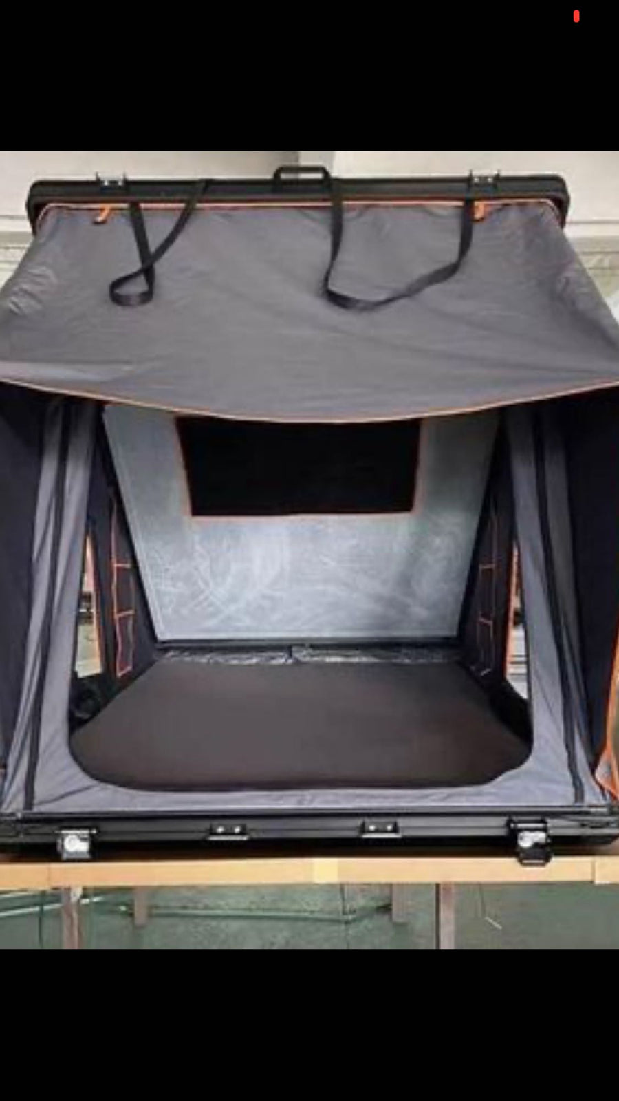 Open vehicle rooftop tent with a mattress and mesh window, ideal for RV rental camping adventures.