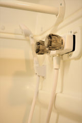 Compact shower in an RV rental, showing clear water control knobs, a flexible hose, and grab bar.