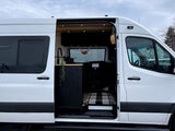 White camper van with side door open, showing modern dark kitchen & wood interior. Ideal for rv rental.