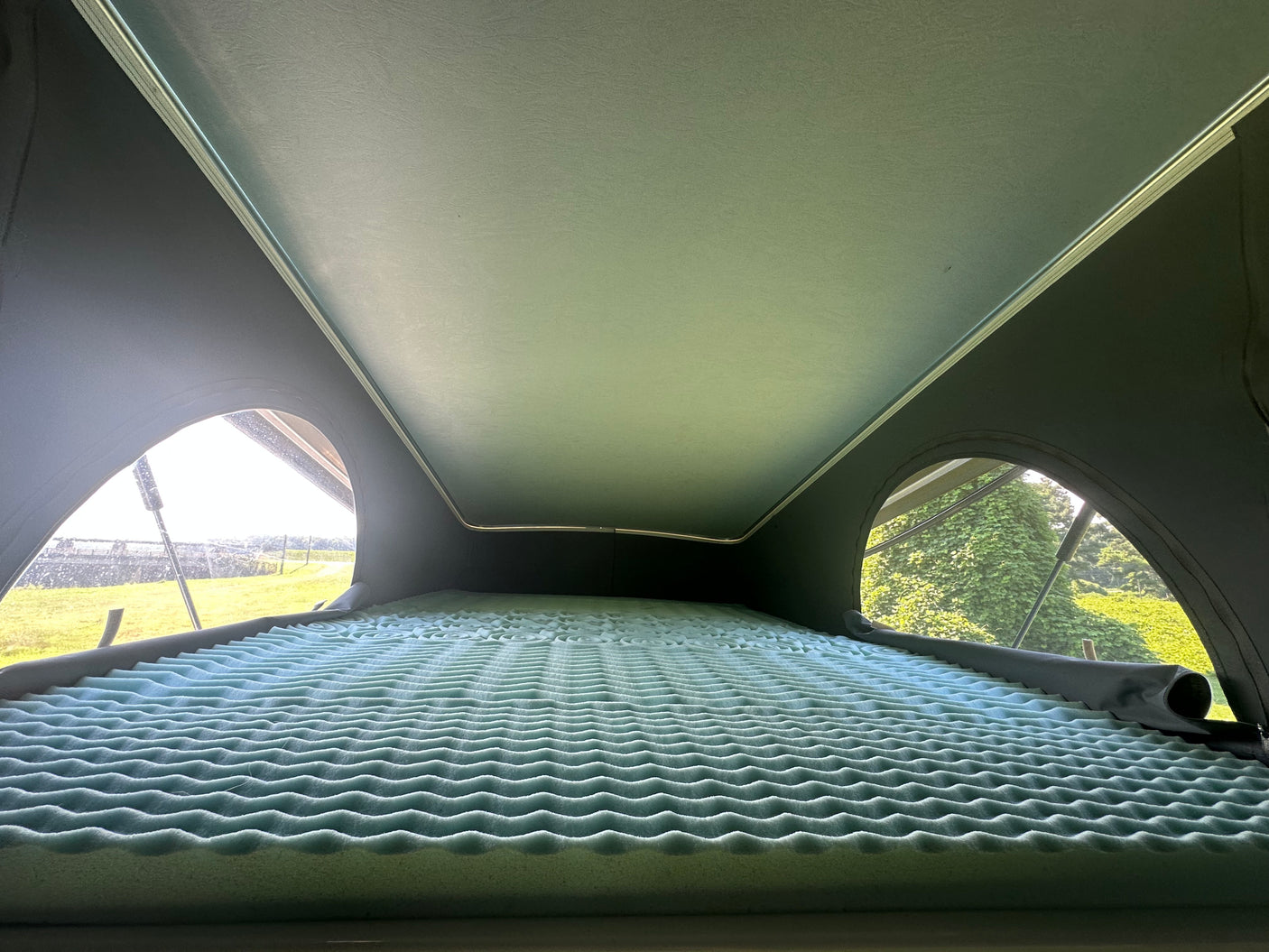 Cozy RV rental pop-top bed features an egg-crate mattress, offering scenic views for your travels.