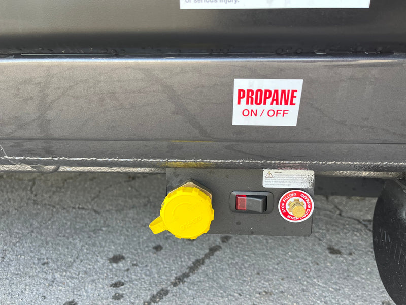 RV rental's propane system: Close-up of the gas fill port with yellow cap, on/off switch, and safety warnings. — photo 8