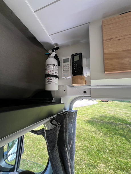 This RV rental's organized interior features a fire extinguisher, MaxxAir fan, and AC remotes for safety and comfort.