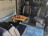 Experience comfortable dining in your RV rental! This van features swivel front seats, a rear bench, and a table with a charcuterie spread.