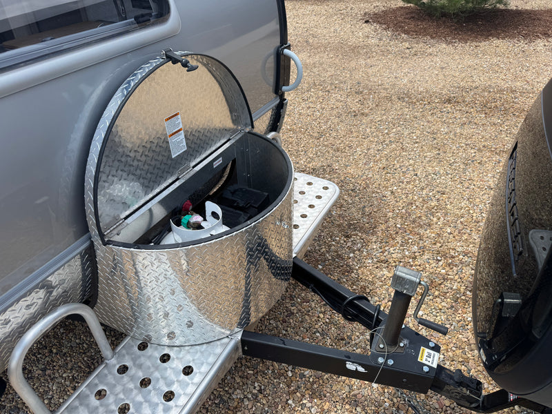 Front hitch area of an RV rental showing an open diamond plate storage box with a propane tank and battery inside. — photo 4