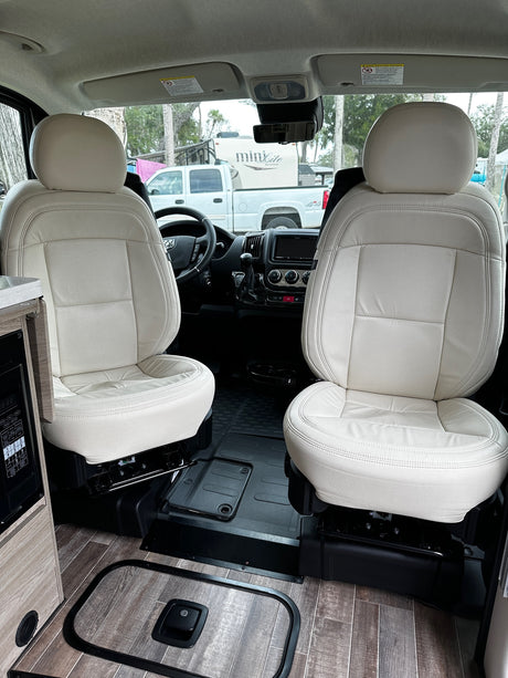 RV rental comfort: Cream swivel seats, modern dashboard, and wood-look flooring define this inviting RV cabin.