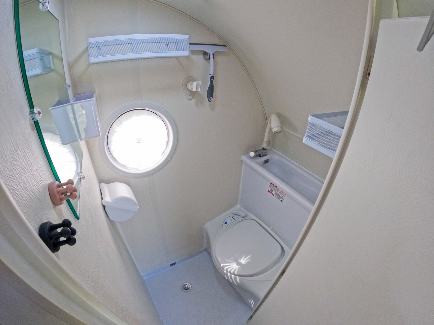 Compact RV rental wet bath with toilet, shower, mirror, and small round window, designed for efficient use of space. — photo 11
