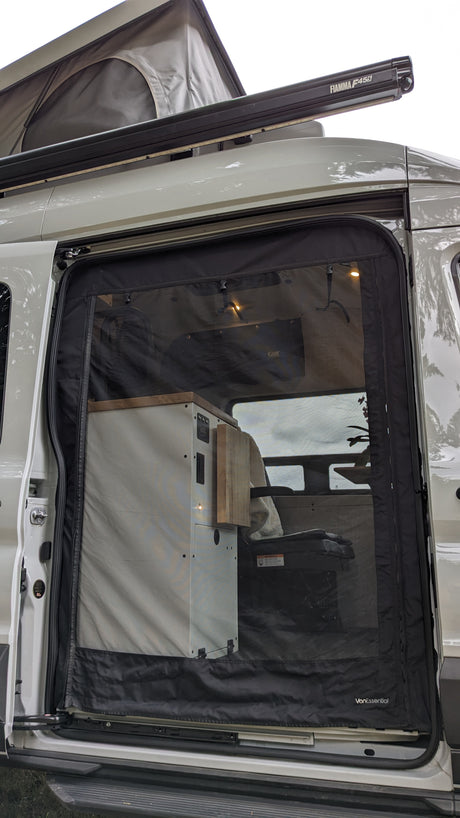 This RV rental pop-top camper van has an open side door, revealing a mesh screen, Fiamma awning, and custom interior.