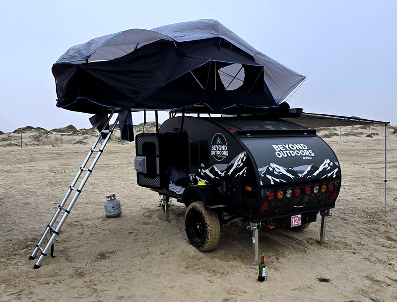  facing ocean waves.|RV rental adventure! This compact camper trailer has an outdoor kitchen & rooftop tent for your overland camping trips.|This Beyond Outdoors off-road teardrop camper — photo 5