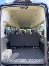 Rear interior of a roomy passenger van, ideal for RV rental, with several rows of seating and generous cargo area.