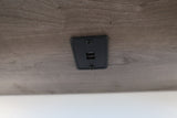 RV rental interior: Built-in USB charging station with two ports on a wood-grain surface, ideal for charging devices.