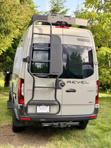 Rear view of a Winnebago Revel 4x4 Sprinter van, an ideal rv rental, featuring a ladder, roof rack, and hitch.