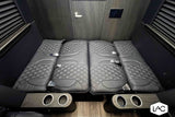 Luxury RV rental interior: plush, diamond-quilted seats laid flat as a bed, with cup holders and a sleek wooden door.