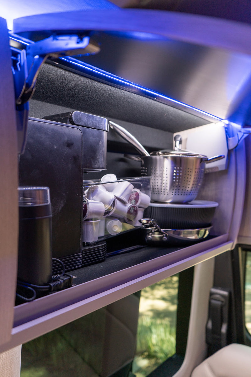 RV rental overhead cabinet with blue LED lighting, neatly storing a coffee maker, pods, grinder, and essential cookware. — photo 16