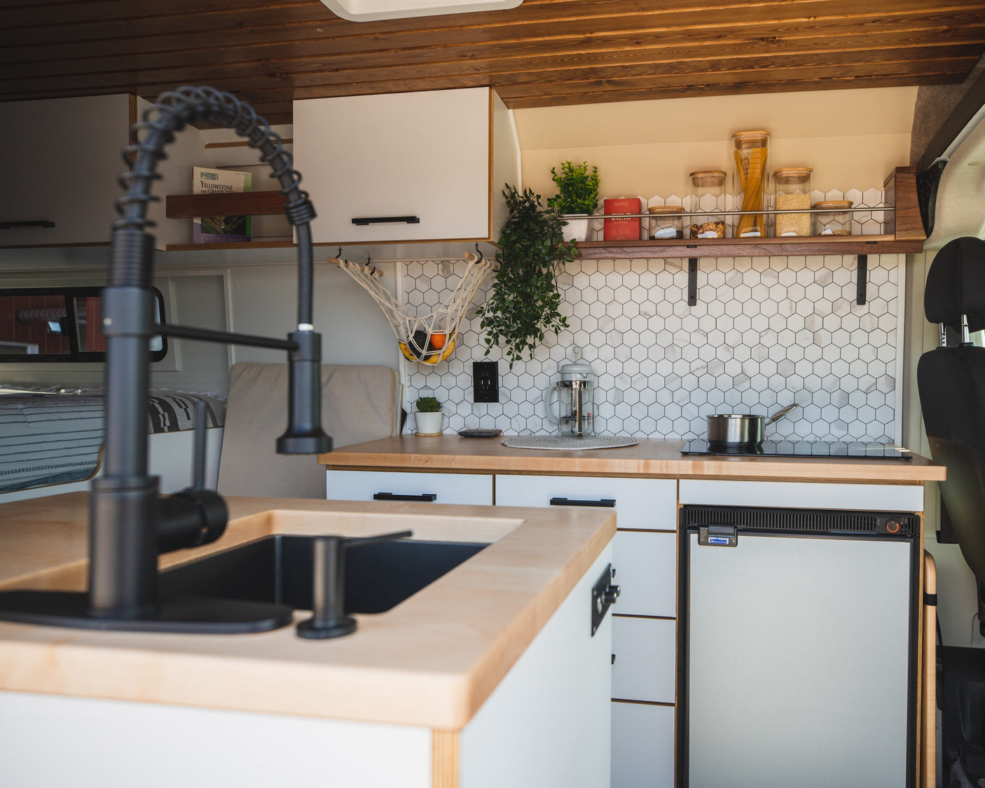 Modern RV rental kitchen with sleek faucet, wood counters, hexagon backsplash, and full amenities, perfect for travel.