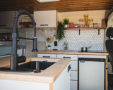 Modern RV rental kitchen with sleek faucet, wood counters, hexagon backsplash, and full amenities, perfect for travel.