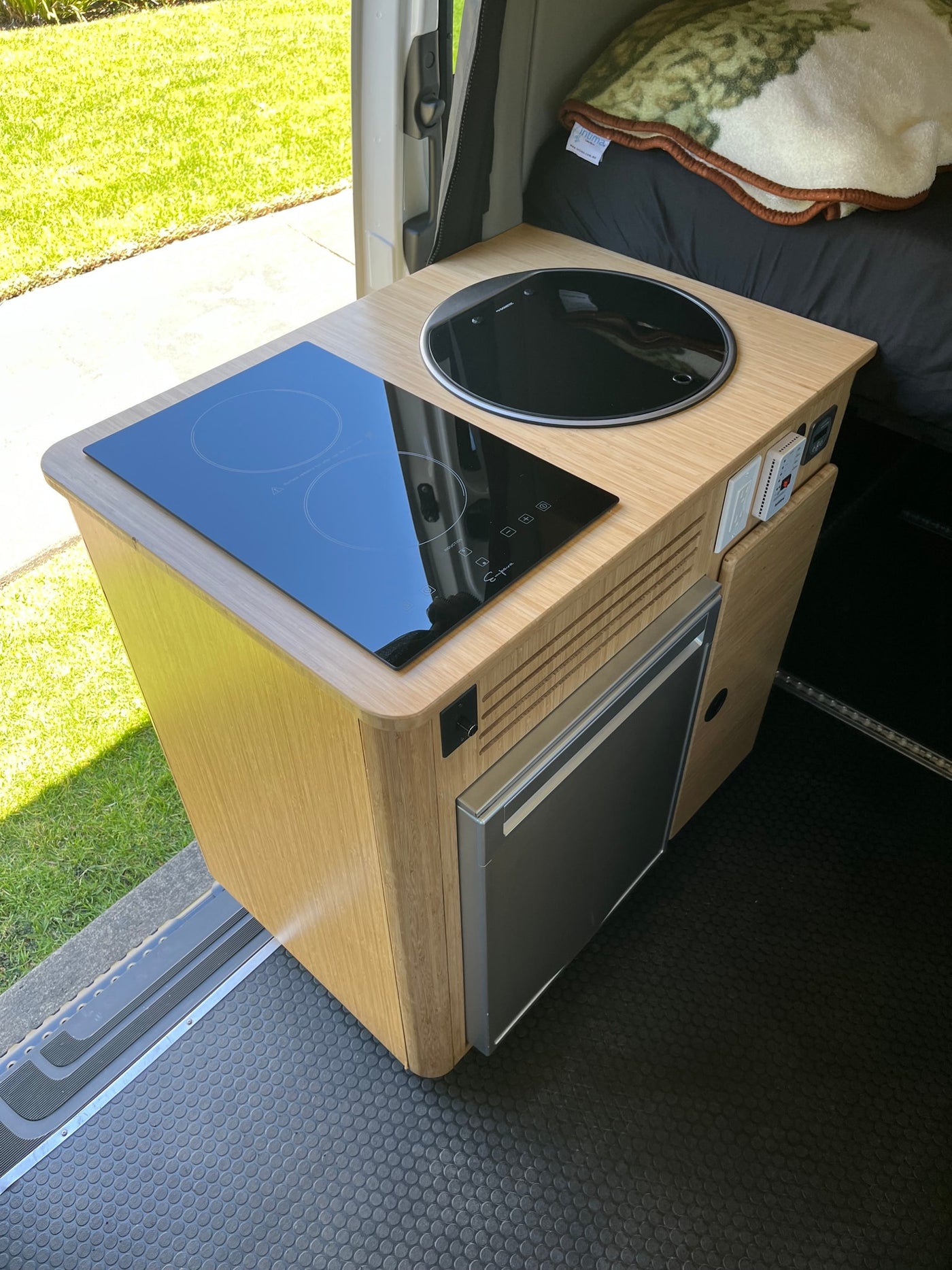 RV rental interior: a compact kitchen module with an induction cooktop, sink, and refrigerator. — photo 8