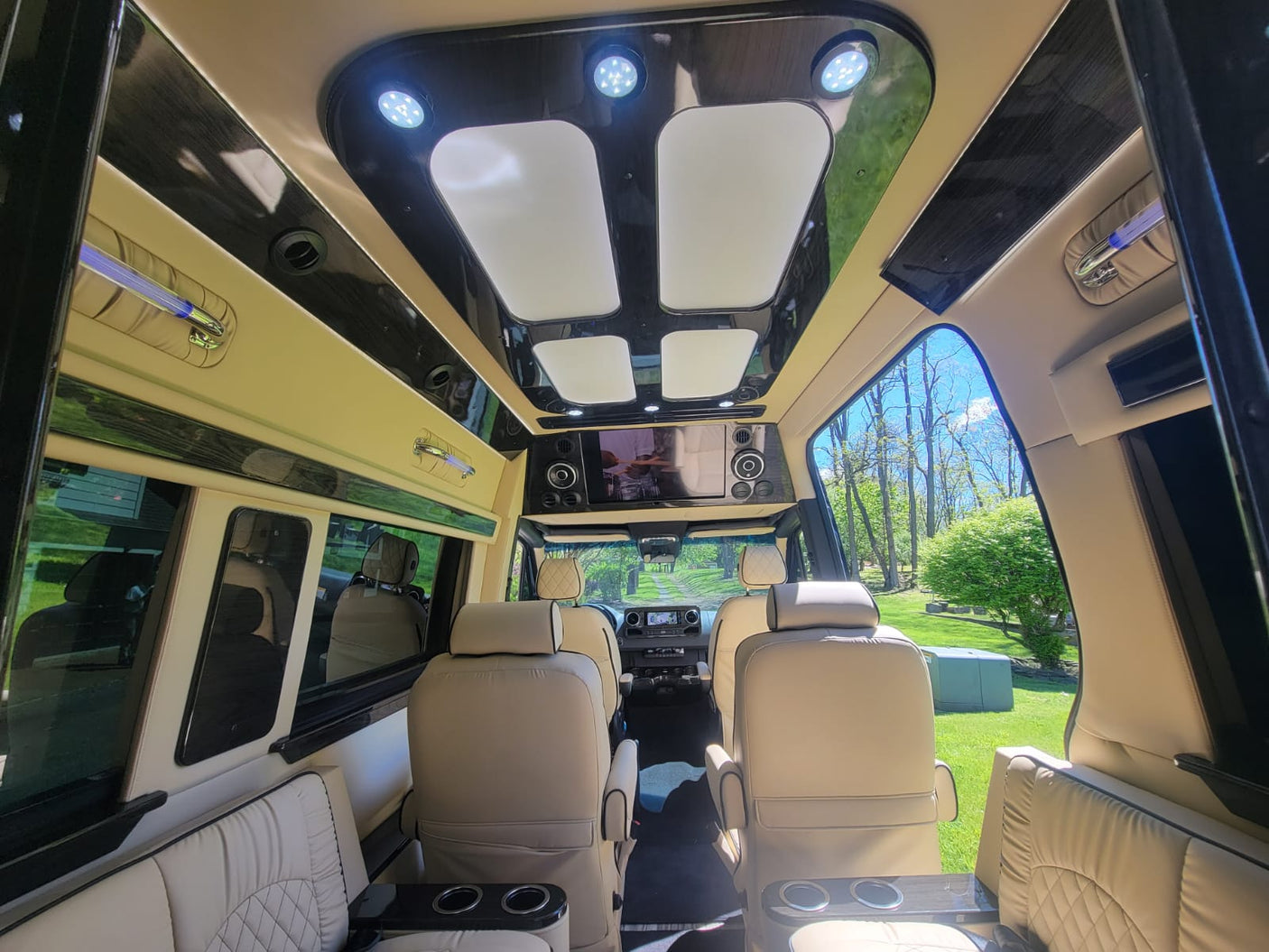 Luxurious RV rental interior with plush beige seating, custom lighting, and entertainment screen. Spacious & ready for travel.