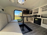Bright RV rental interior features a cozy dinette, outdoor view from the window, TV, and fireplace for travel.