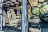 Luxurious rv rental interior with cream leather captain's chairs, modern ceiling lights, and wood-look flooring visible through an open door.