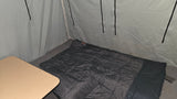 RV rental camping setup: interior with a comfortable sleeping bag, wooden table, and soft-sided walls.