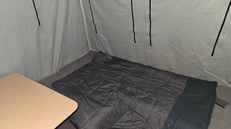 RV rental camping setup: interior with a comfortable sleeping bag, wooden table, and soft-sided walls. — photo 6