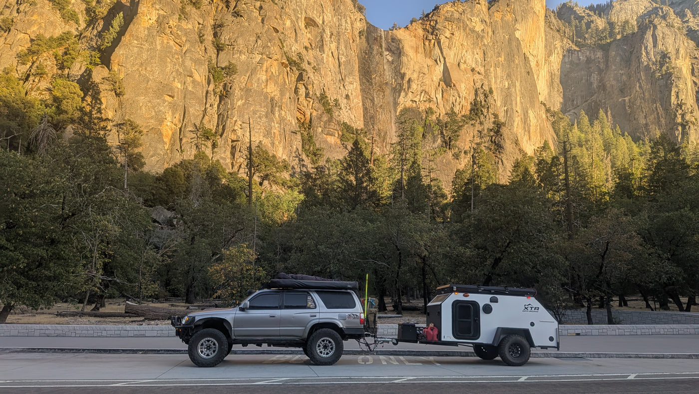An overland 4Runner tows an XTR off-road teardrop trailer before huge sunlit cliffs and trees, ideal for an RV rental trip. — photo 15