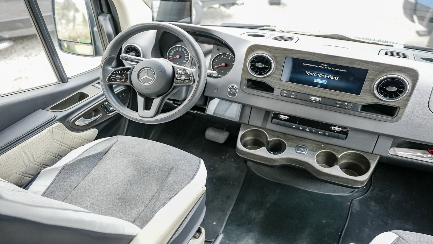 Spacious Mercedes-Benz RV rental interior with a modern dashboard, large screen, and comfortable driver's seat.