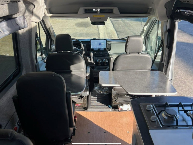 RV rental: Inside a camper van showing front cabin with display, swivel seats, dining table, and built-in stovetop. — photo 3
