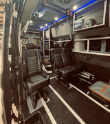 Custom van RV rental with plush black leather seating, track flooring, overhead storage, and blue LED lighting.