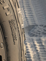 Close-up of an RV rental tire (Gravel Commander) on rippled sand, ready for your next adventure.