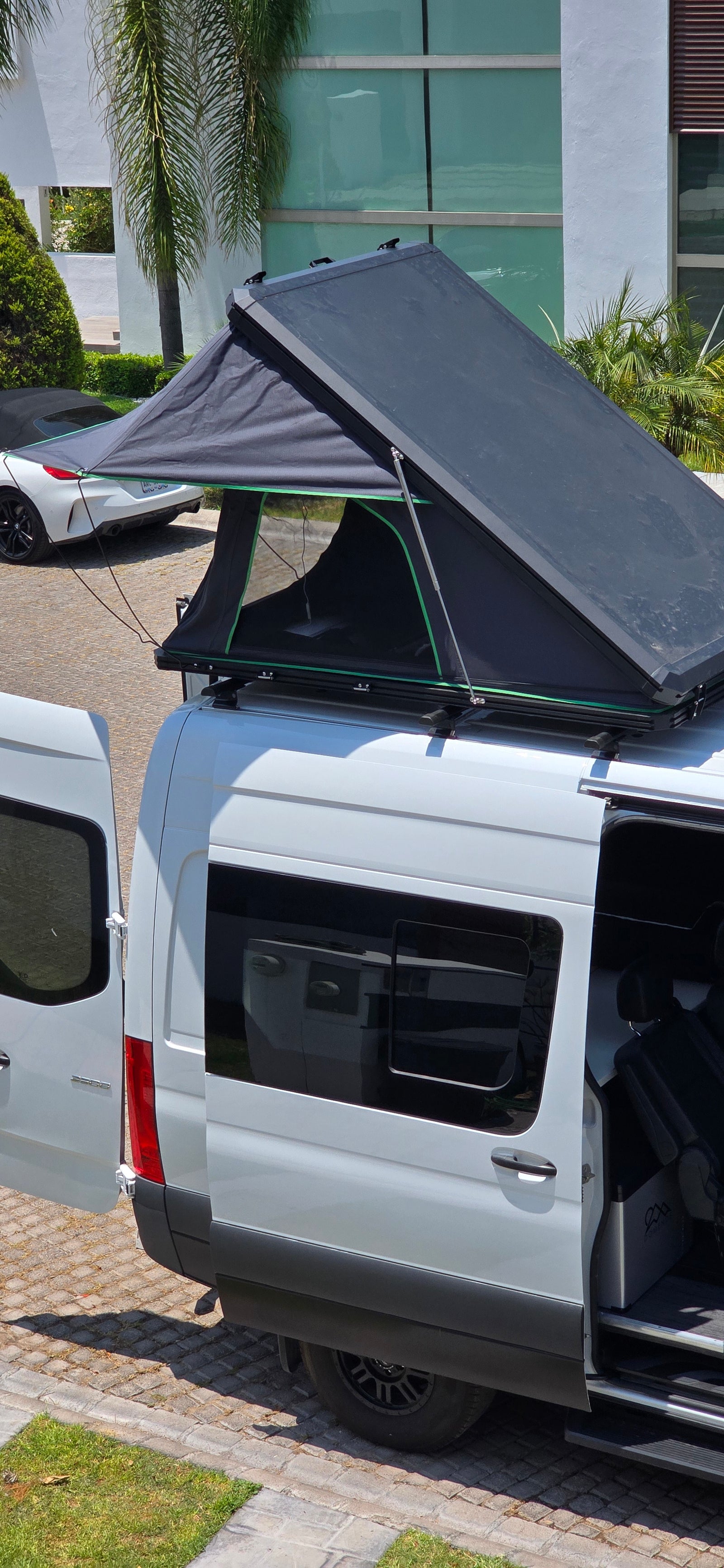 Explore with this rv rental! White camper van featuring an open rooftop tent and accessible interior.