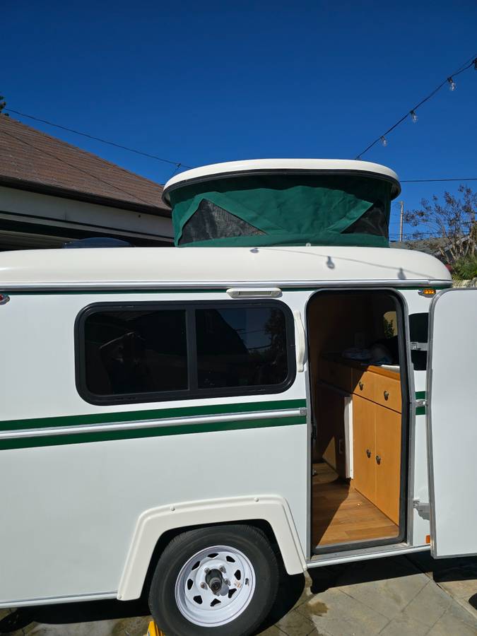  great for RV rental adventures.|White compact travel RV rental with green stripes & pop-top. Door open — photo 2