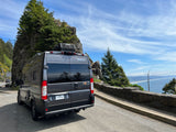 Gray Winnebago Solis rv rental parked cliffside on the Oregon coast, overlooking a vast blue ocean and distant beach.