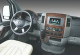 RV rental interior: A modern van's driver's area with dark steering wheel, wood trim, and large central display screen.