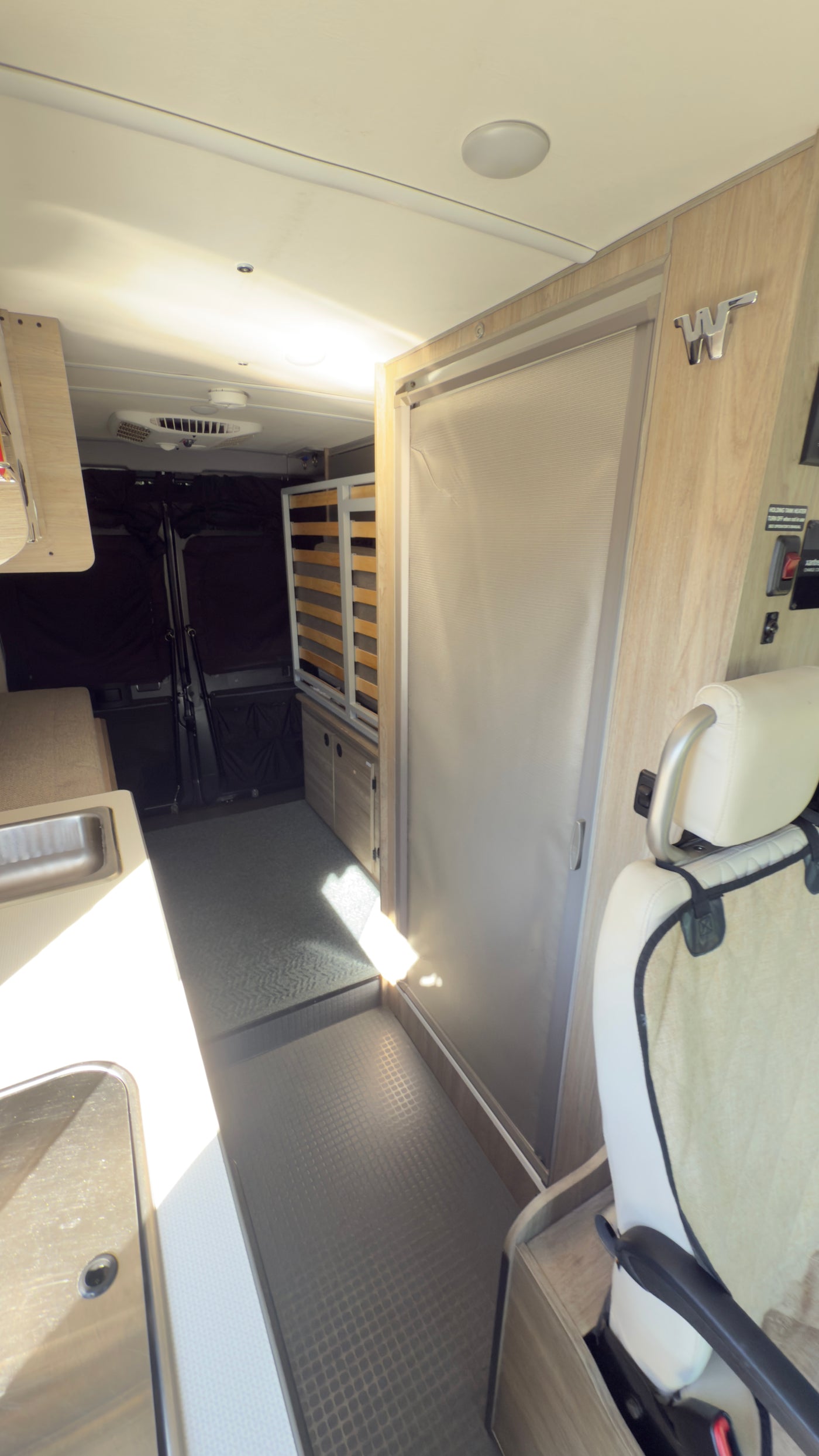 Modern RV rental interior: galley, convertible bed frame, and front seat area. Bright and functional design. — photo 12