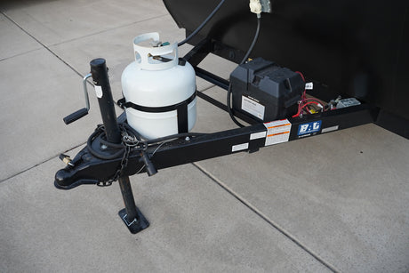 Essential components of an **rv rental** trailer: a white propane tank, battery box, and jack on the hitch.