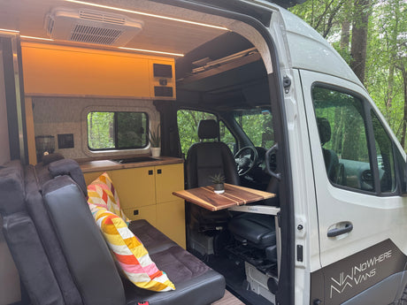 Step inside this modern camper van RV rental, featuring a well-appointed kitchen, cozy seating, and a movable table.