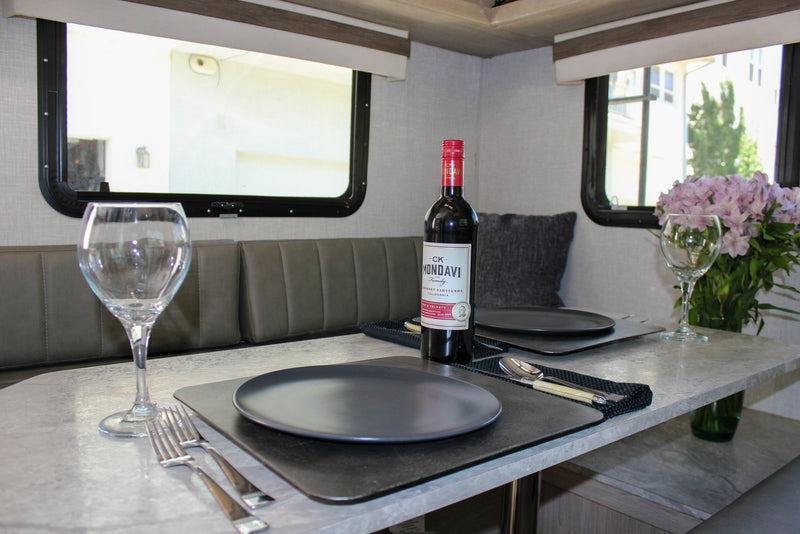 An inviting dinner setup in an RV rental, featuring a bottle of CK Mondavi wine, two place settings, and fresh pink flowers. — photo 13