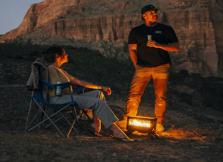 RV rental trip: Two people unwinding by a warm portable heater, enjoying drinks in the fading light.