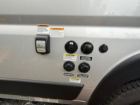 RV rental utility panel: power (30A), cable, city & fresh water, and black tank flush connections on the side.