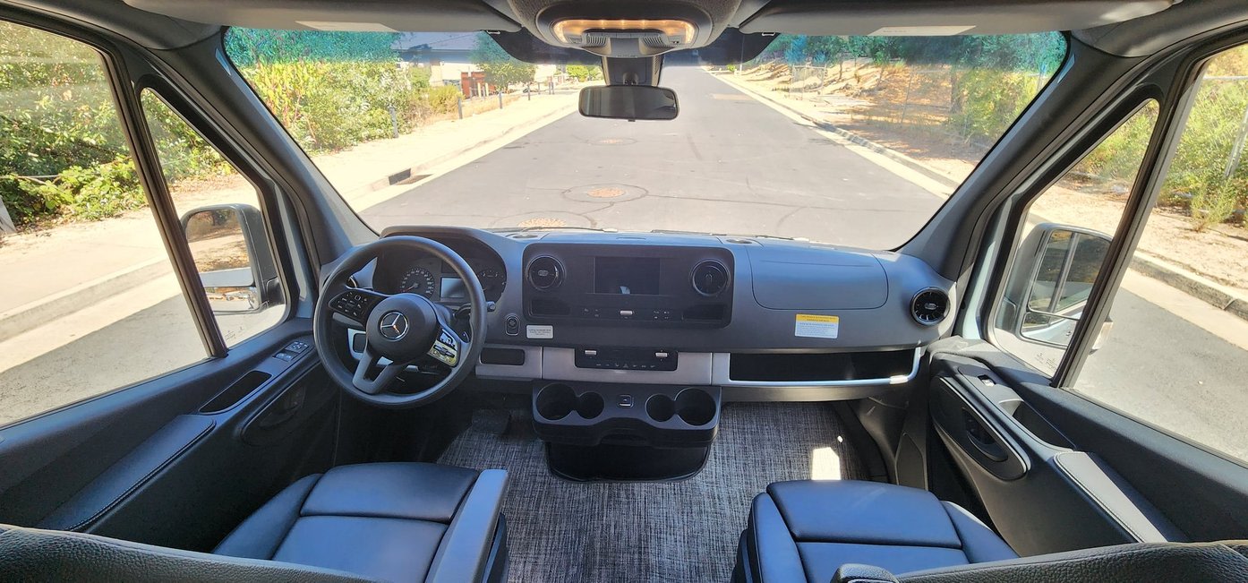 Spacious interior of an RV rental van showing the modern cockpit, driver's view, and the road ahead.