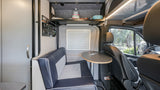 RV rental interior shows blue/white dinette, adjustable table, control panel, and overhead storage, designed for efficient travel.