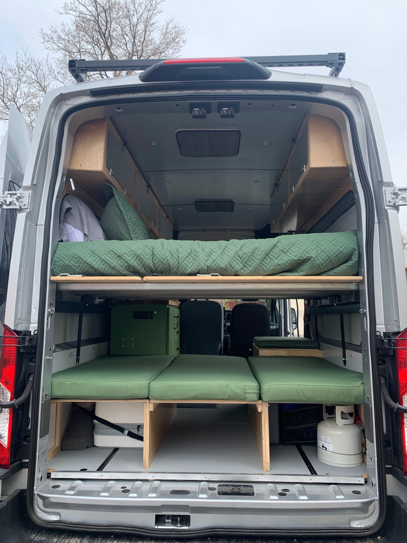 Inside an RV rental: a custom camper van interior featuring a comfortable bed, bench seating, and built-in storage.