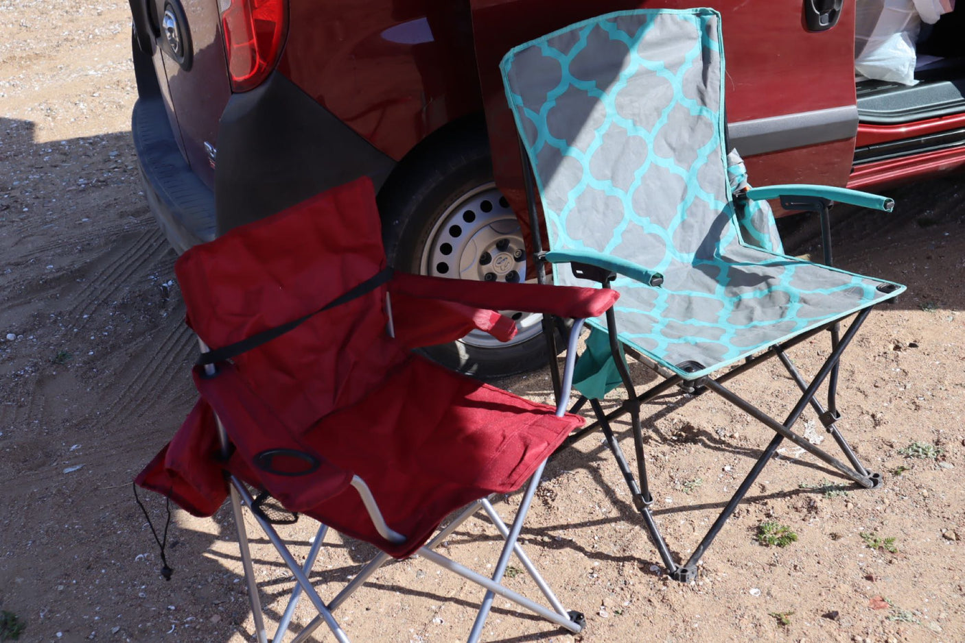 Two portable camping chairs sit beside an RV rental, ready for a relaxing outdoor break at a campsite.