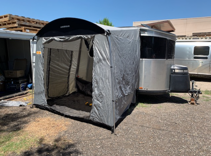 Silver Airstream travel trailer with attached grey tent awning for expanded outdoor living, great for an rv rental. — photo 9