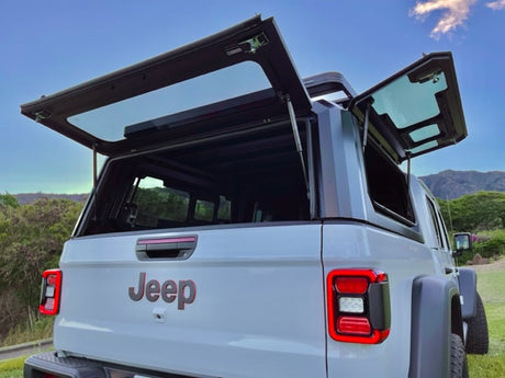 This light grey Jeep Gladiator truck RV rental features its multi-access truck camper panels open, ready for adventure.