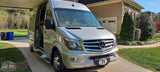 Silver Mercedes-Benz Sprinter RV rental parked on a suburban driveway with awning extended